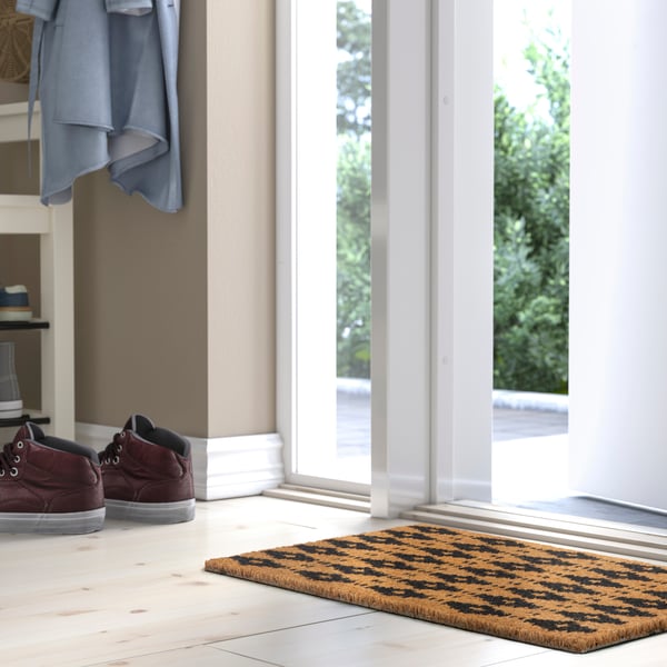 A coir/geometric BETALVÄG door mat in the hallway