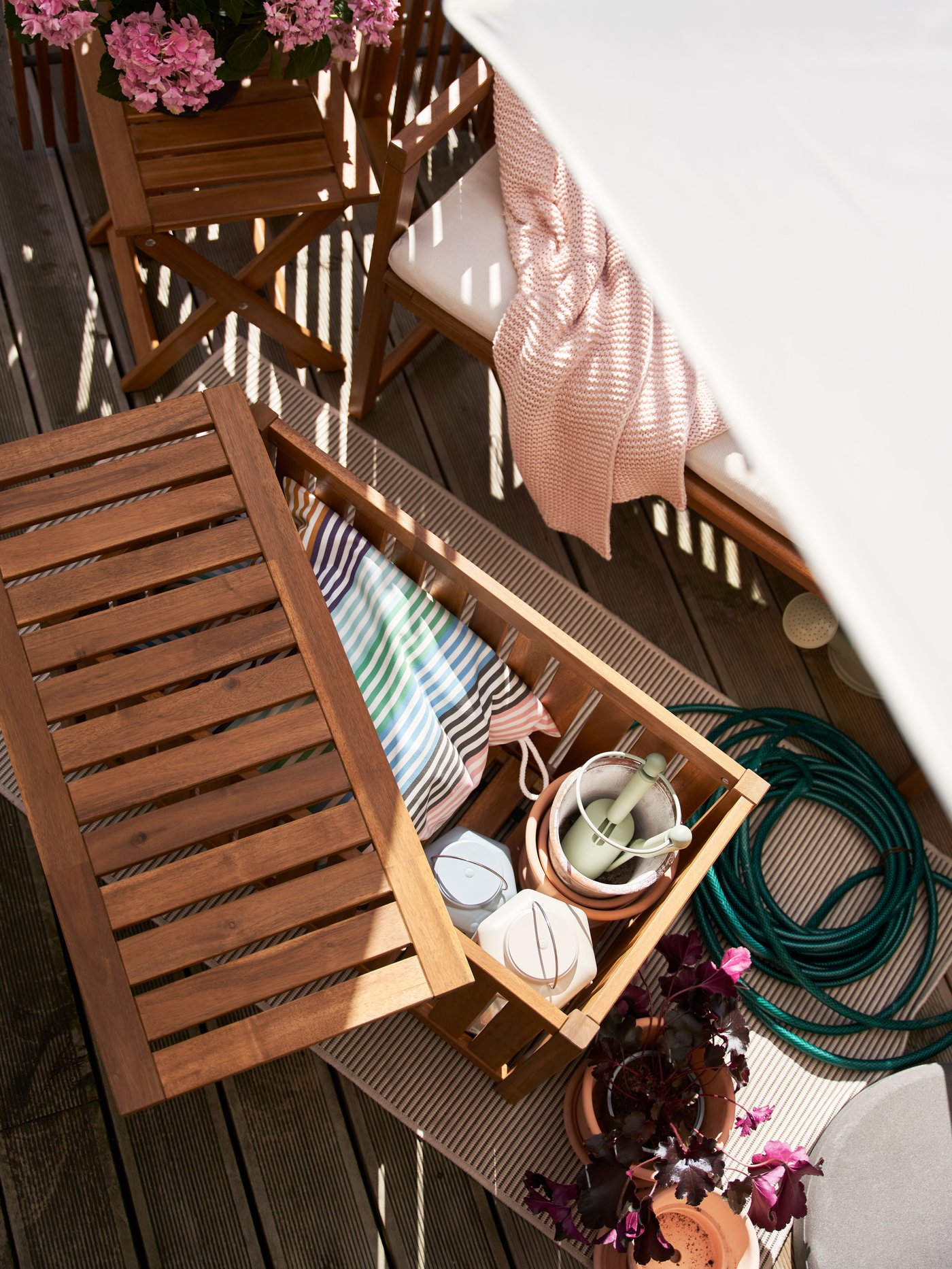 מבט מלמעלה על קופסת אחסון NÄMMARÖ מעץ שיטה בגוון חום בהיר, שהמכסה שלה פתוח מעט וחושף כלי גינון.