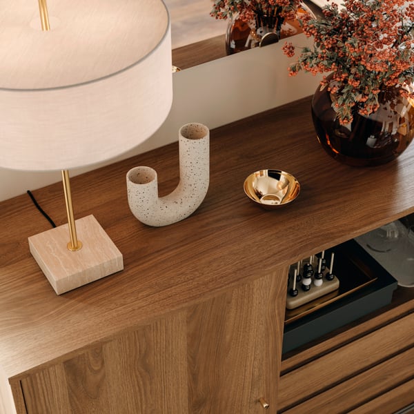 Träsideboard höstdekorerad med en lampa, små skålar och en vas med höstlöv.