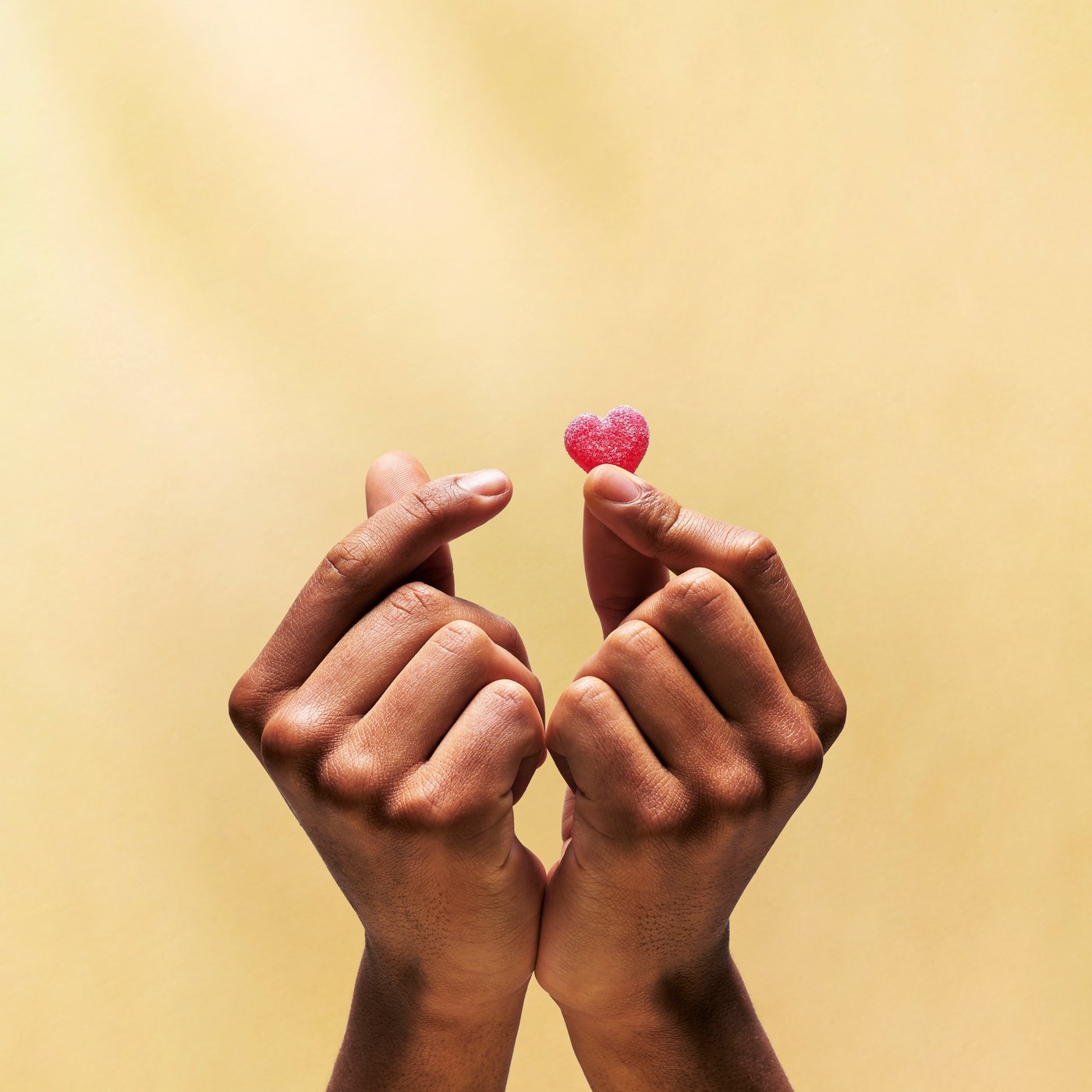 Hands holding out a gummy heart.