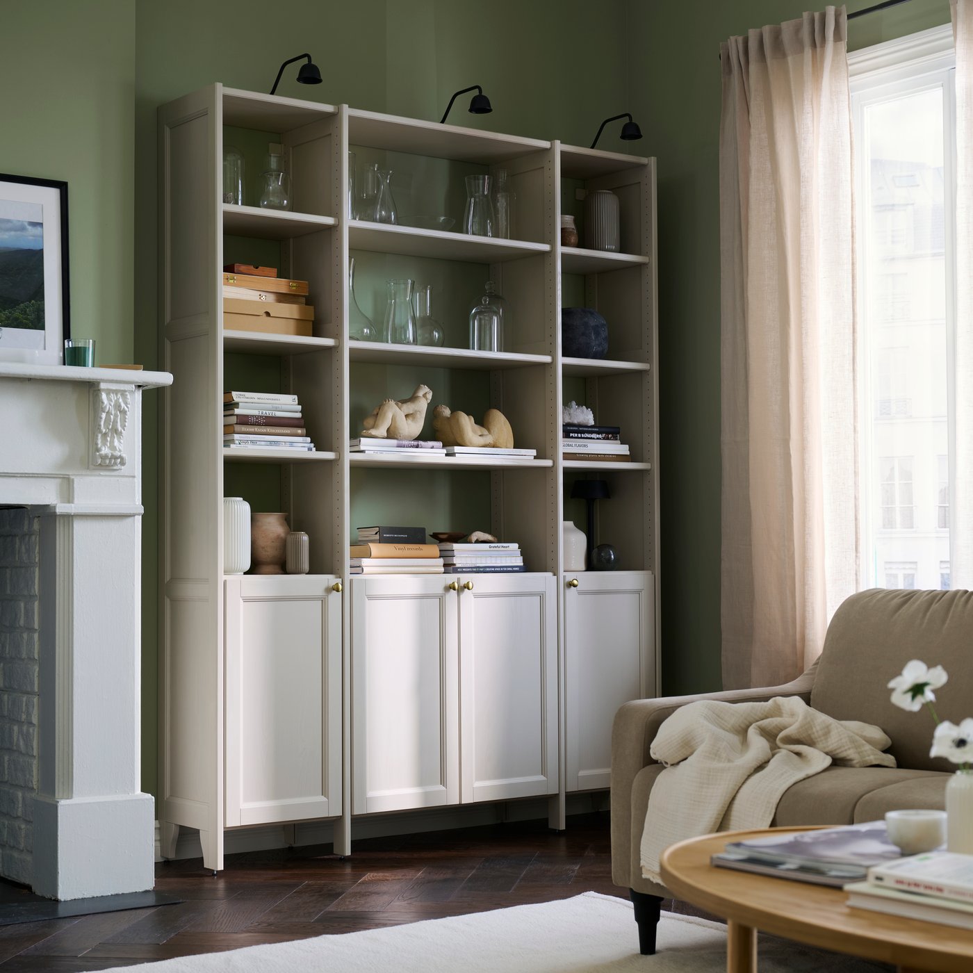 GULDDRAGARE storage system in a living room with a green wall and shelves with vases and books.