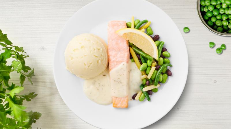 Lachsfilet mit Fisolen, Bohnen, Kartoffelpüree mit Dillsauce auf einem Teller präsentiert.