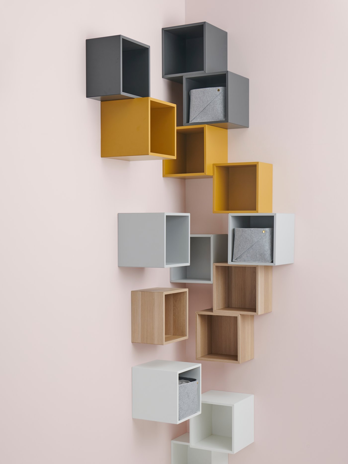 Salón con armarios de pared de varios colores, montados en la pared, con cestos grises de tela en su interior.