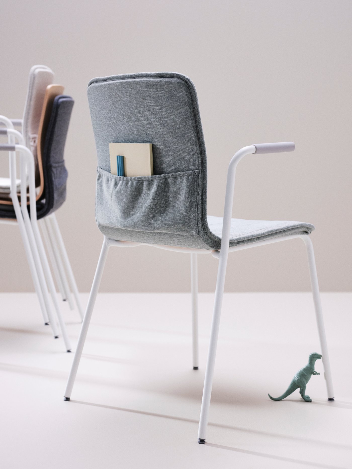 A room with LÄKTARE chairs with covers in different colours. Three are stacked, the lone one has a notebook in its pocket.