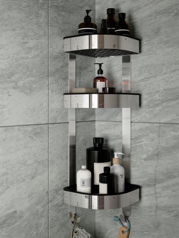 A BROGRUND corner wall shelf unit of stainless steel, with bathroom products on it, is mounted in a corner with grey tiles.