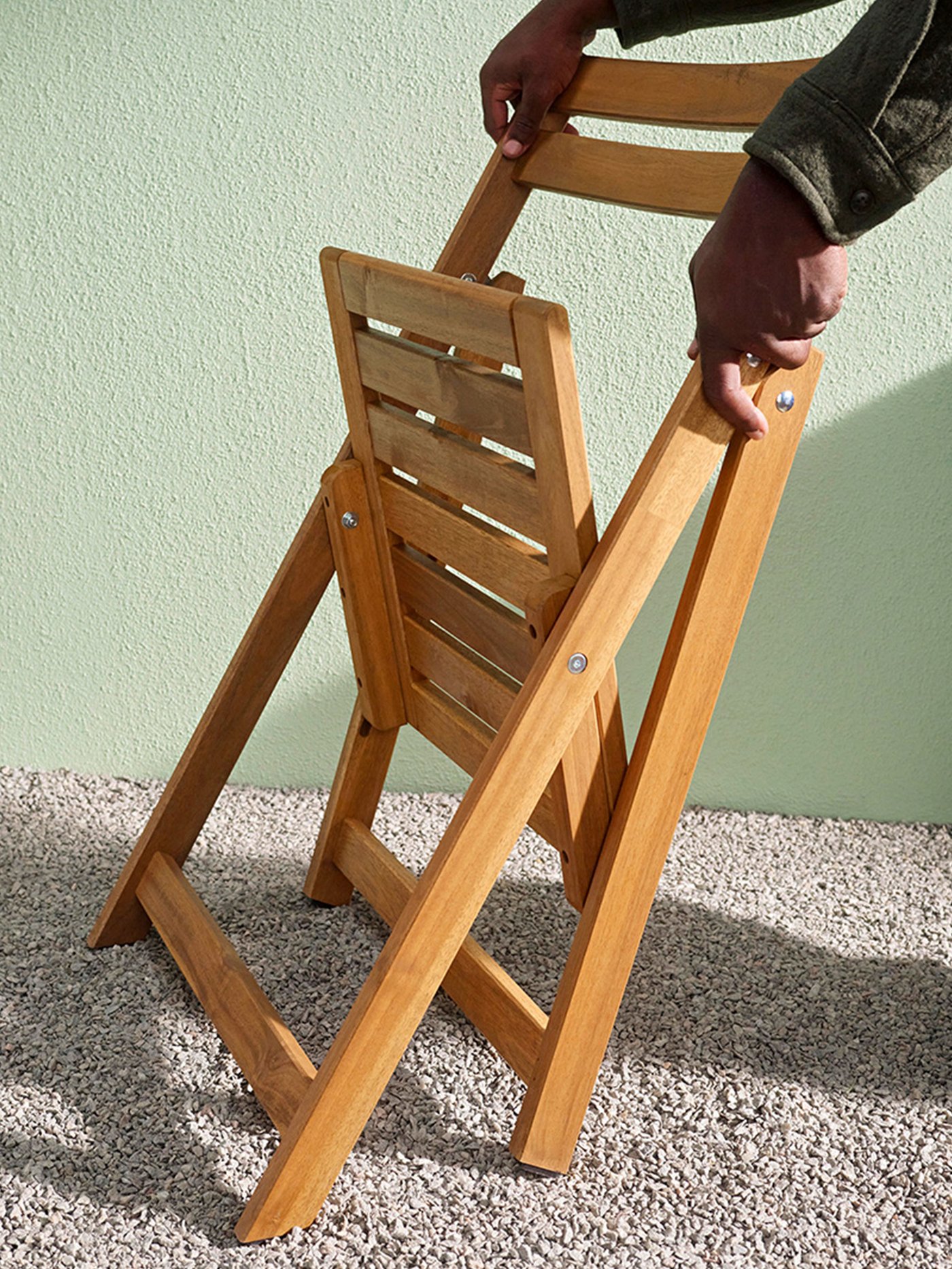 Sedia pieghevole NÄMMARÖ in legno chiaro per esterni, pronta all’uso sul terrazzo.