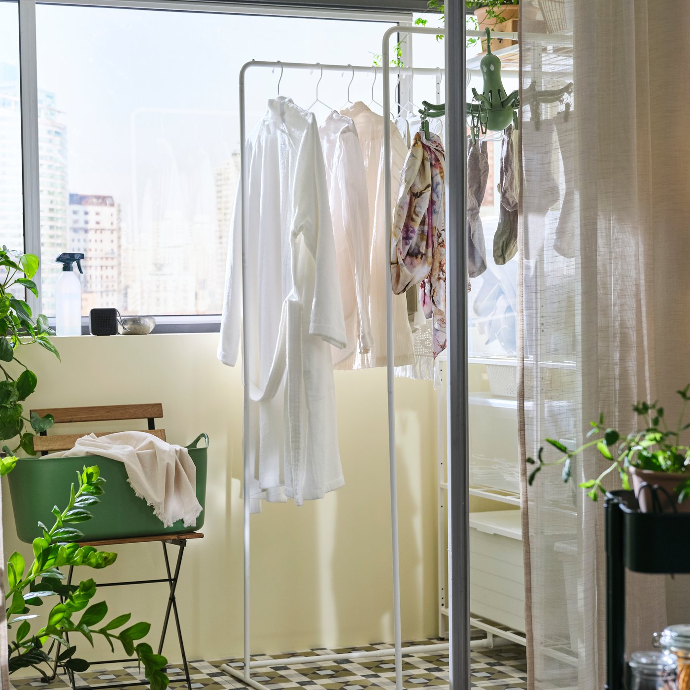 Blick durch eine Schiebetür auf einen Balkon mit einem JOSTEIN Regal und einem Wäschetrockner. An diesem hängt Kleidung.