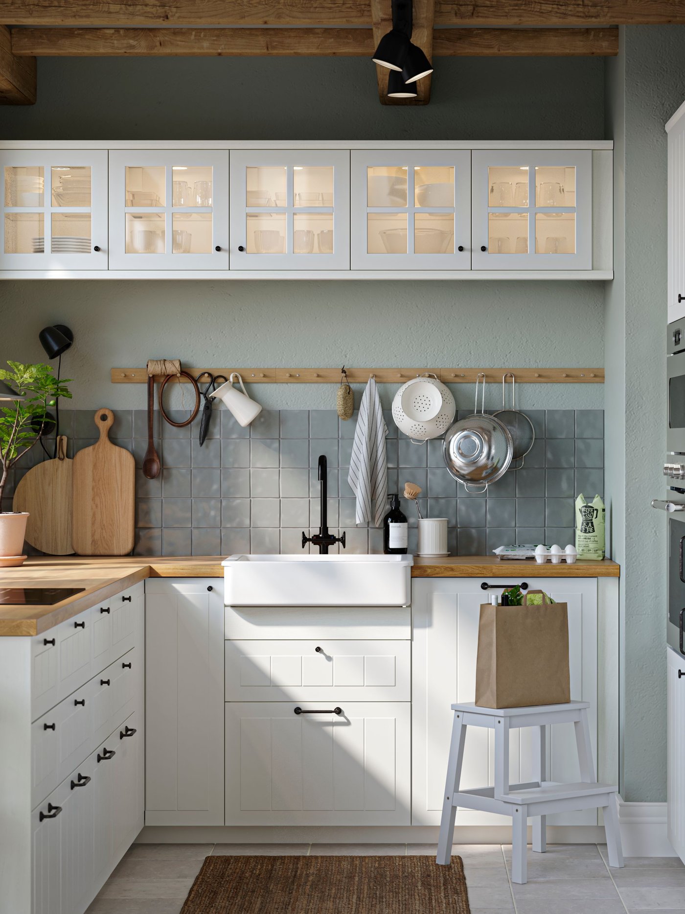 A kitchen with white STENSUND drawer fronts and glass doors, oak effect worktops and a white sink bowl with visible front.