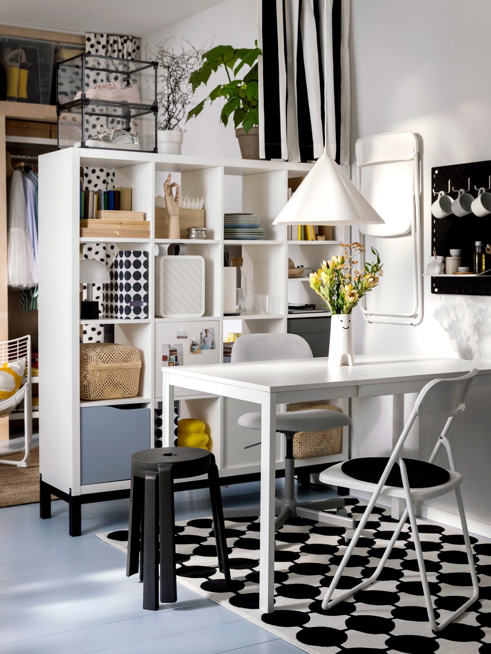 Unha cadeira xiratoria, unha cadeira pregable VIHALS e dous tallos amontoados xunto a unha mesa extensible VIHALS nun comedor pequeno.