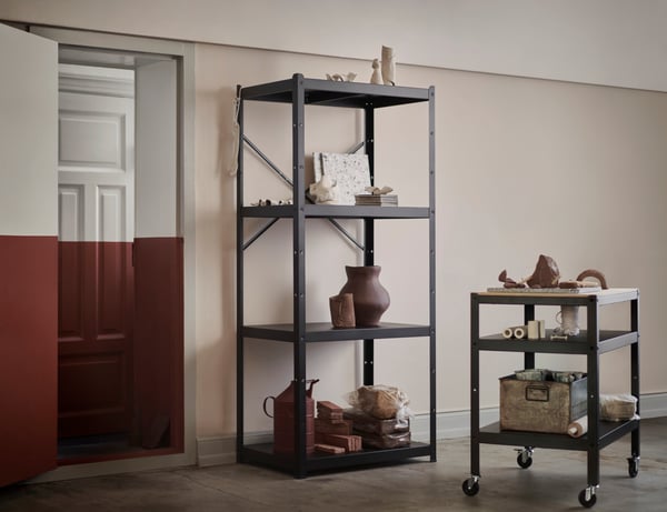 Dos gabinetes color negro con accesorios de greda encima, atras una puerta color rojo con blanco.
