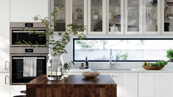 A kitchen with high-gloss RINGHULT fronts and wall cabinets with HEJSTA glass doors has a kitchen island in the foreground.