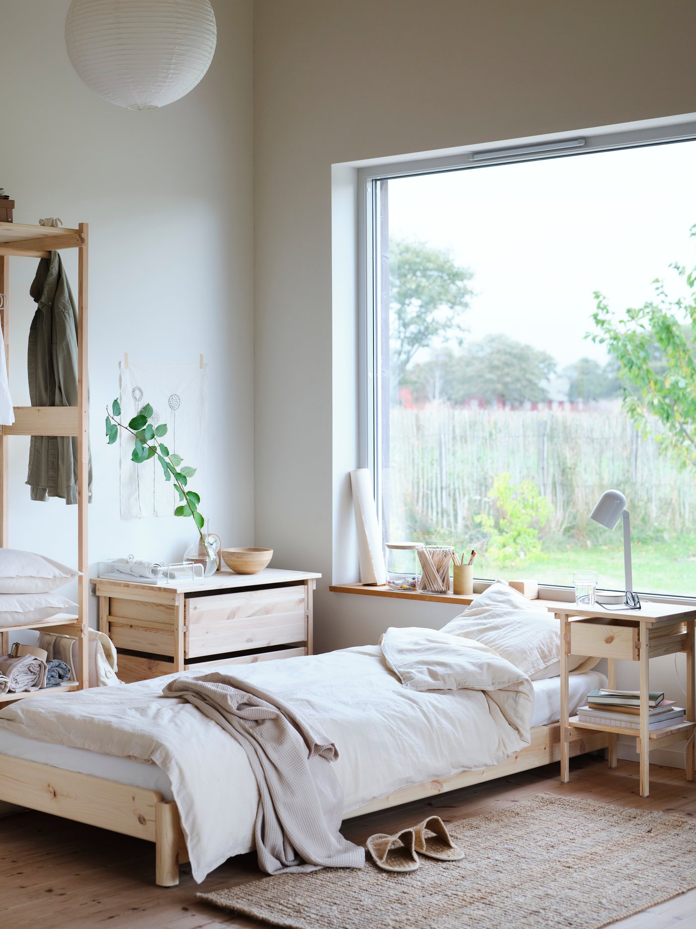 In einem hellen Schlafzimmer sind helle Holzmöbel und ein Einzelbett zu sehen.