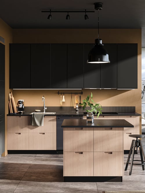 A sunlit kitchen with a combination of FRÖJERED and KUNGSBACKA fronts, a DALFRED bar stool in front of a kitchen island.