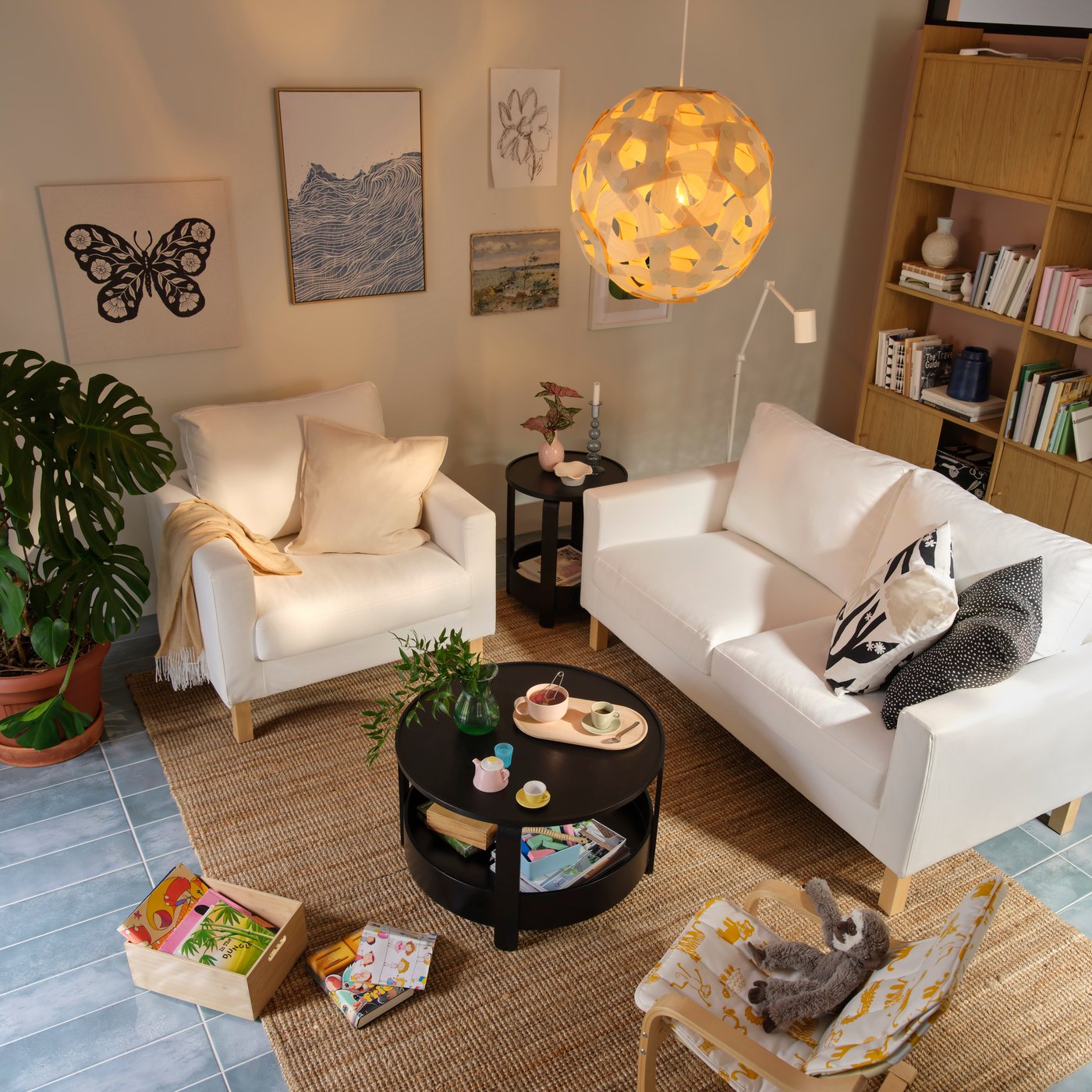 A light living room with a white SALTSJÖBADEN two-seat sofa and armchair surrounded by decorative items and plants.