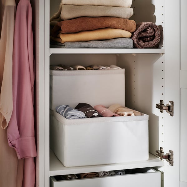 Two shelves in a PAX/TYSSEDAL wardrobe combination. SKUBB boxes with clothing in are on one, and jumpers are on the other.