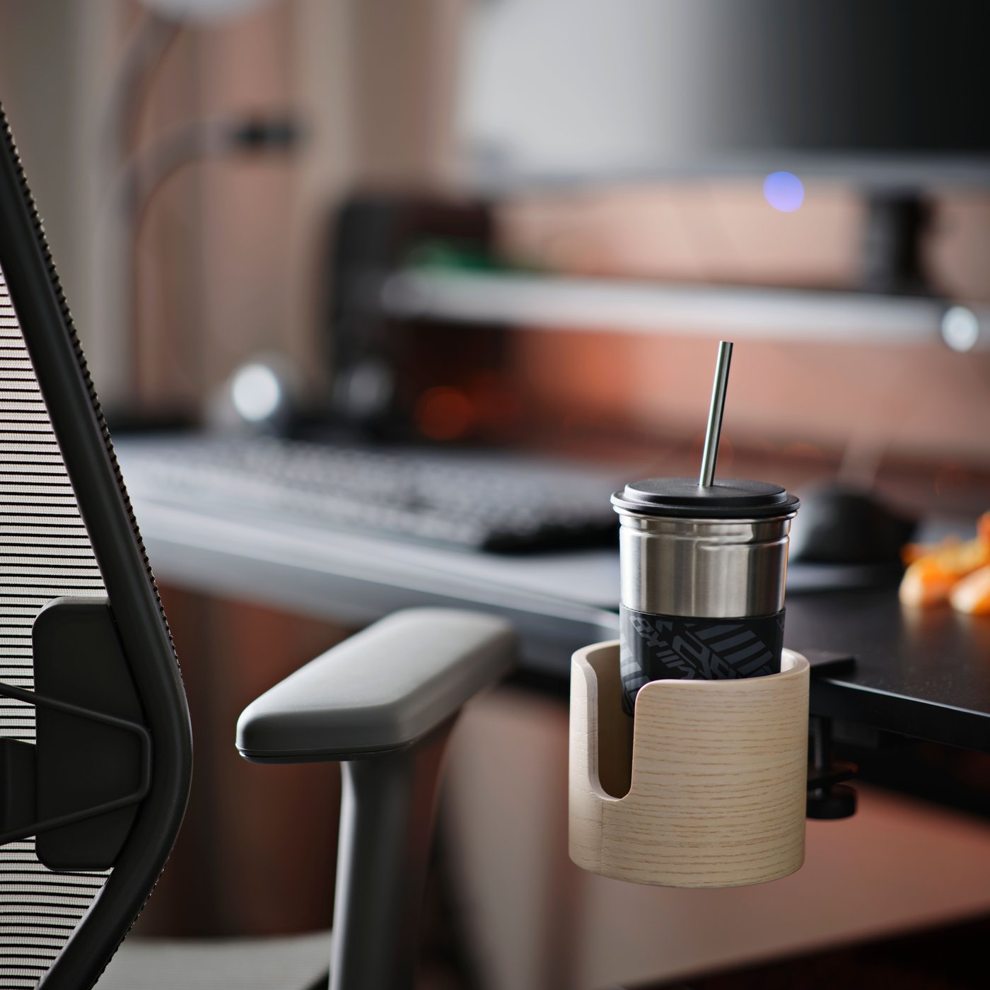 Uchwyt na kubek LÅNESPELARE przymocowany do biurka gamingowego.