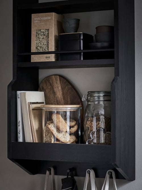 Close-up on kitchen open storage unit wall shelf mounted to the wall, made of wood, with retro design and hooks.