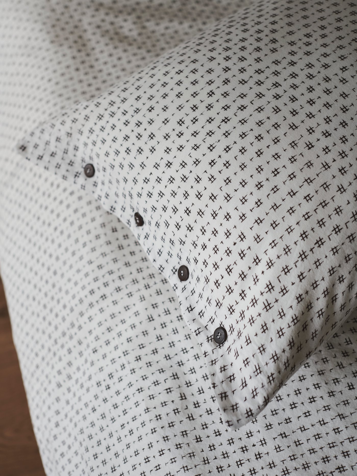 Detail ložního prádla VÄGTÅG zvýrazňující motiv inspirovaný Japonskem a dřevěné knoflíky.