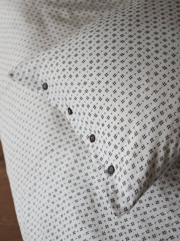 Close-up of VÄGTÅG bed linen highlighting the Japaneses-inspired motif and wooden buttons.