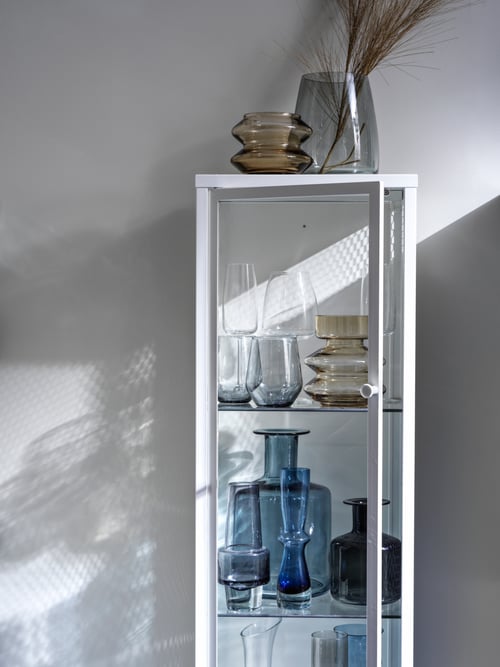 Several types of crystal vases and glasses displayed and stored inside the opened BAGGEBO glass door cabinet.
