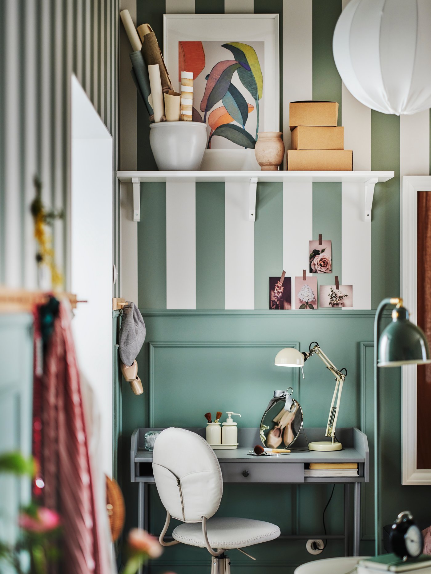 A grey HAUGA desk in the corner of a green room with a beige BJÖRKBERGET swivel chair in front and a FORSÅ work lamp on top.