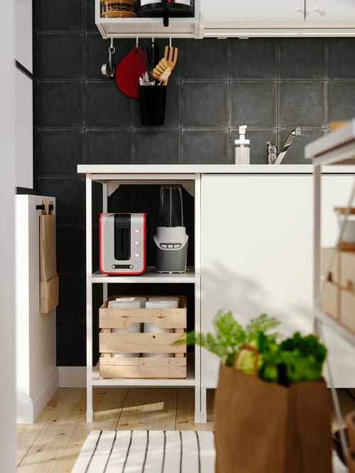 Küchenbereich mit einem ENHET Regalrahmen für Unterschrank, u. a. mit einem KNAGGLIG Kasten, einer LILLTRÄSK Arbeitsplatte, einer ENHET Tür, ENHET Stange für Haken und SKOGSVIKEN Haken mit verschiedenen Utensilien.