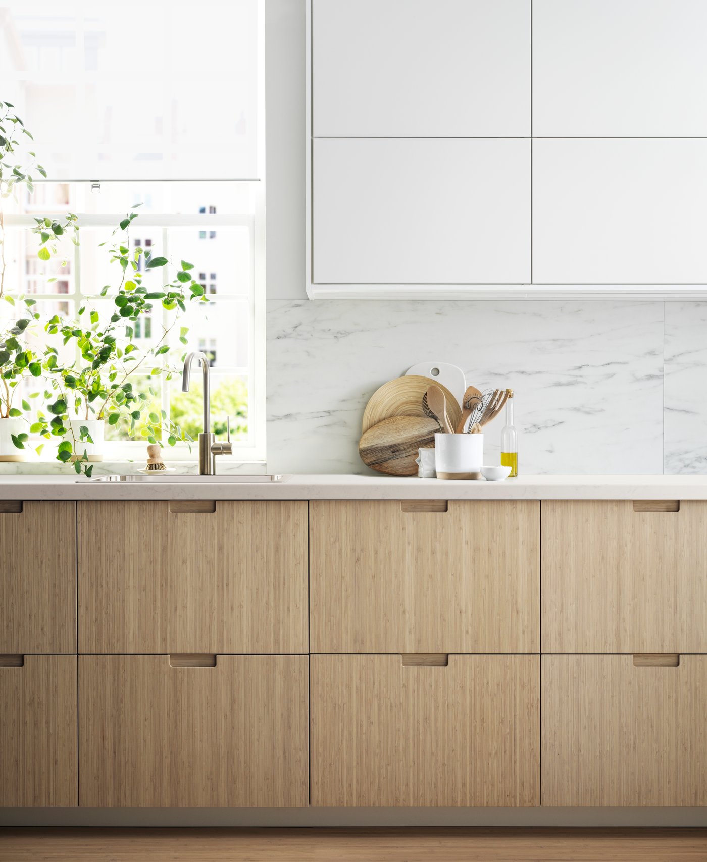 Een keuken met licht bamboe FRÖJERED ladefronten en witte bovenkasten.