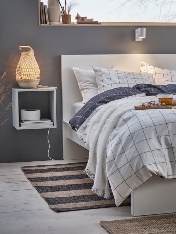 A black/beige UGILT rug, flatwoven in the bedroom