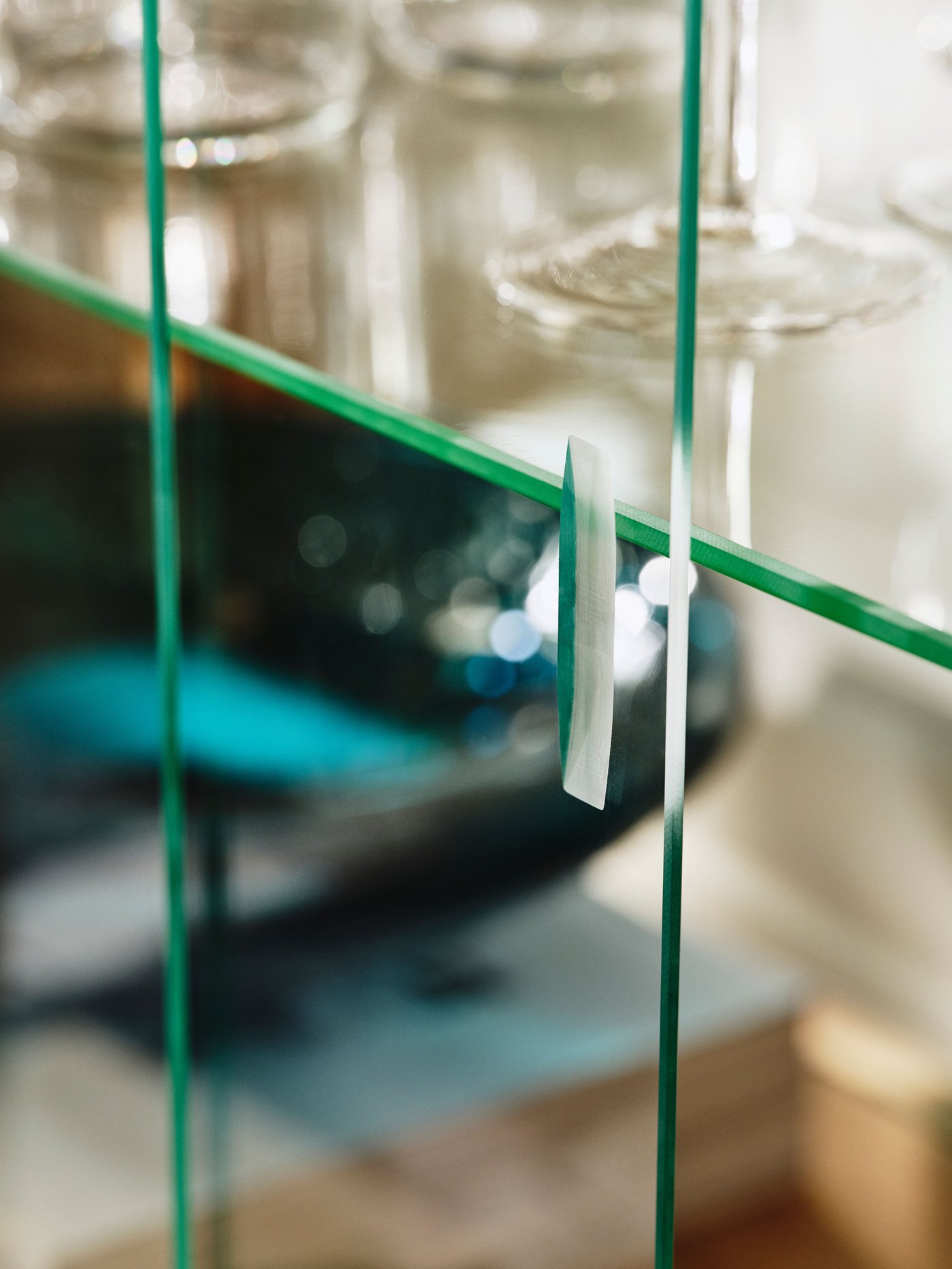 A close-up of the doors of an oak veneer STOCKHOLM 2025 glass door cabinet. Glasses and a bowl are seen through the doors.