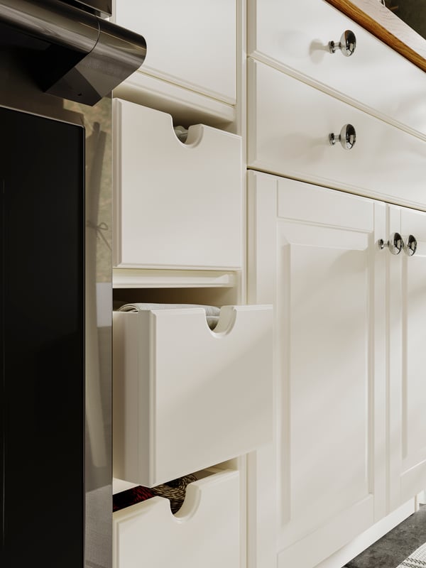 Des étagères contenant des boîtes TORNVIKEN blanc cassé, des portes et façades de tiroirs BODBYN blanc cassé et des boutons ENERYDA chromés.