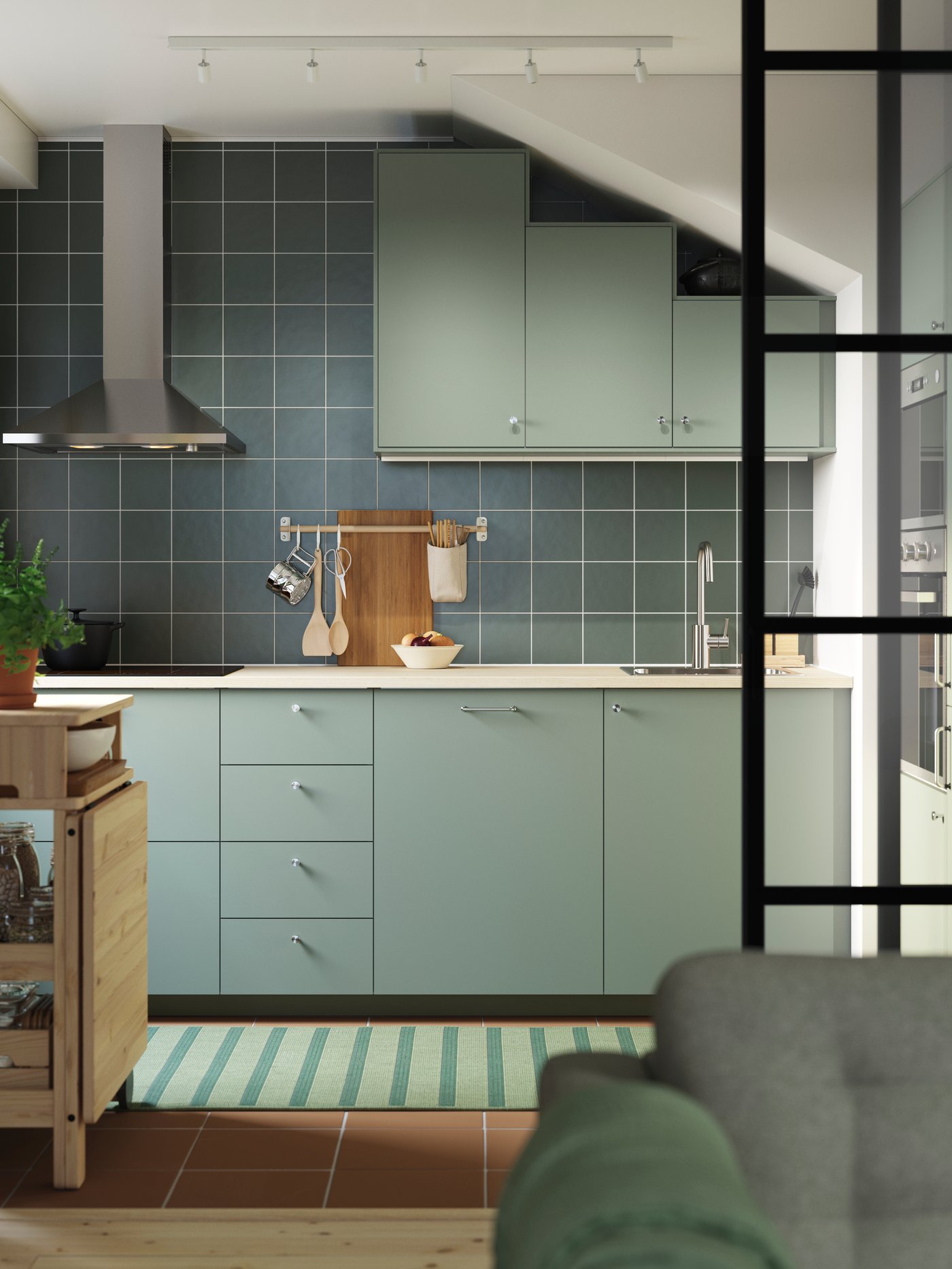 Une cuisine NICKEBO gris-vert avec des meubles bas et des meubles hauts sous un plafond incliné et une table à abattant mobile RESARÖ.