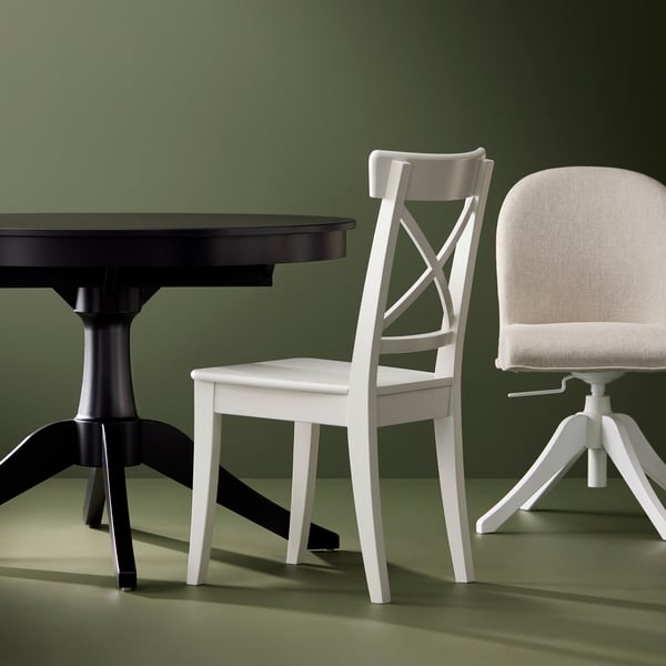 A black ROSENTORP extendable table, a white ROSENTORP chair and a swivel chair on a green background.