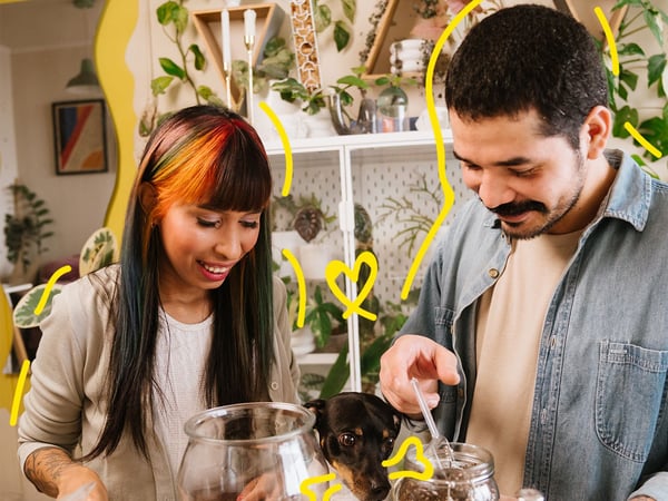 Una dona i un home decoren pots de vidre amb terra i plantes.