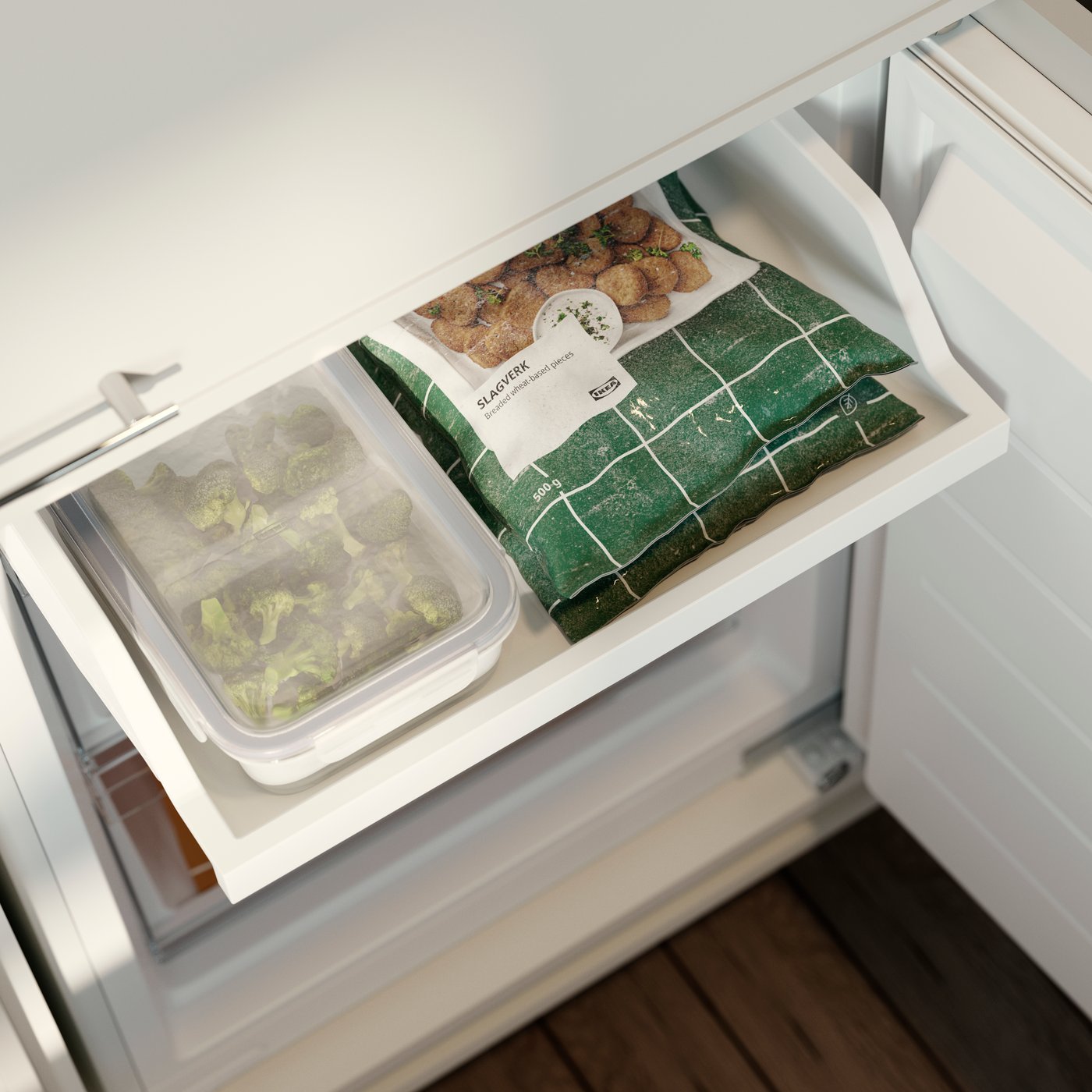 IKEA 365+ food container with vegetables stored in a freezer drawer next to frozen food packages.