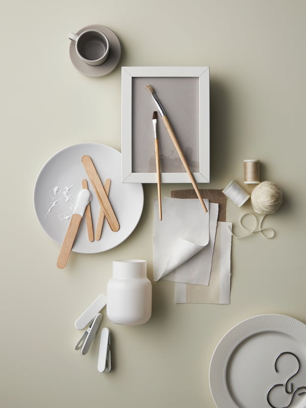 A scattered mix of items with a white FLITIGHET side plate, a beige DINERA espresso cup and saucer, fabric and string.