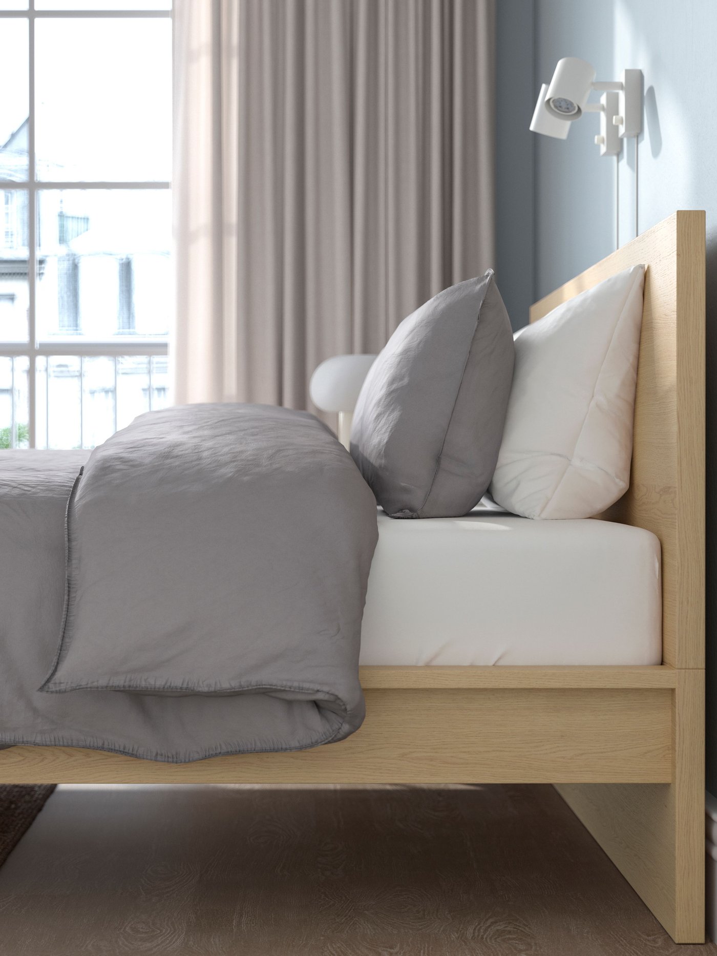 Una cama MALM en madera con un colchón y ropa de cama encima. 