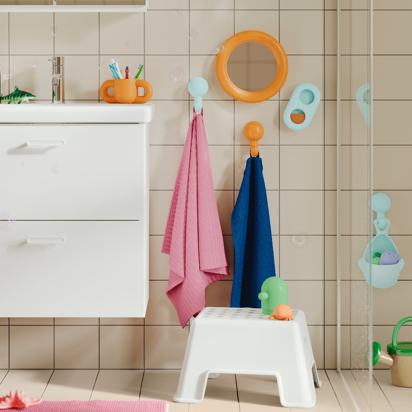 A BOLMEN step stool on the floor, a sink and colourful towels and accessories on the wall in child-friendly height.