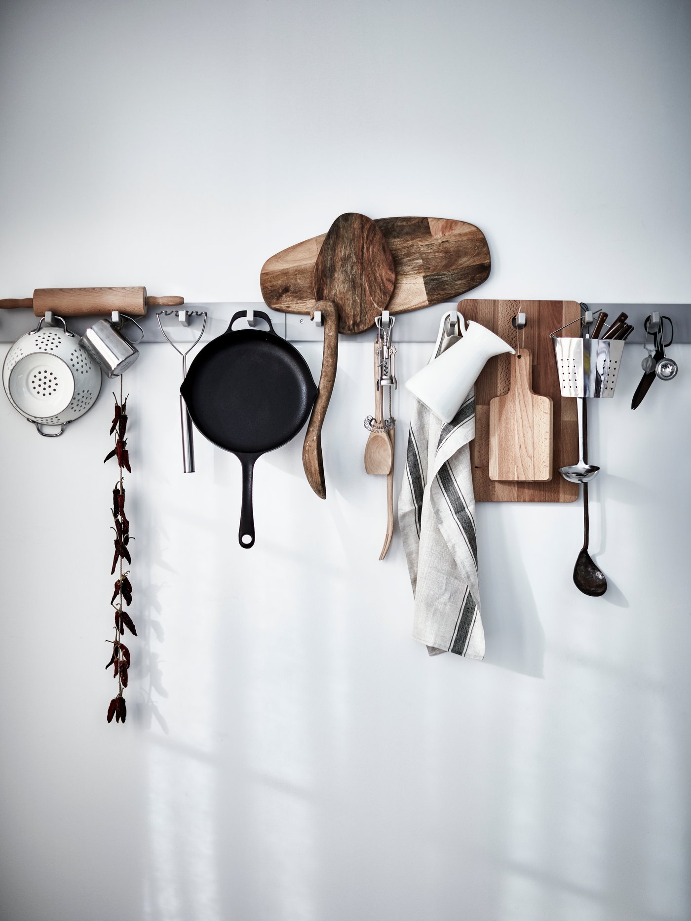 A FINMAT saute pan and other cooking accessories are placed on racks in the kitchen.