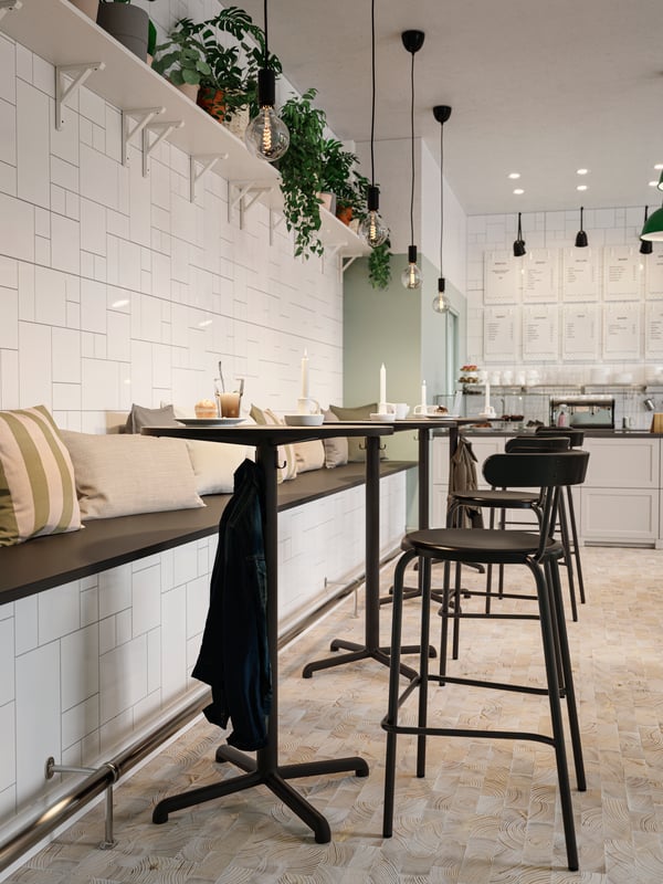 Four anthracite café tables put together to create one long table, coffee and pastries, chairs and dark green pendant lamps.