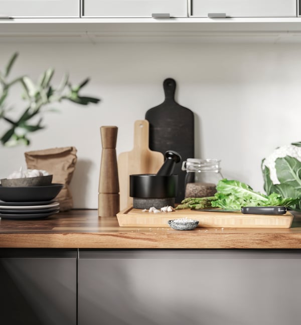 Herbs and spices are prepared using an AEDELSTEN Pestle and mortar and chopping board in a white kitchen