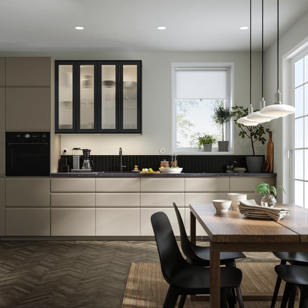 Een moderne keuken met beige fronten en een zwart bovenkastje.