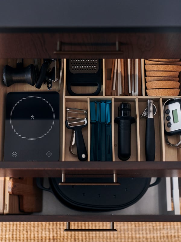 A kitchen drawer with a VOXTORP front opened, revealing cutlery in an UPPDATERA cutlery tray and knives in a knife tray.