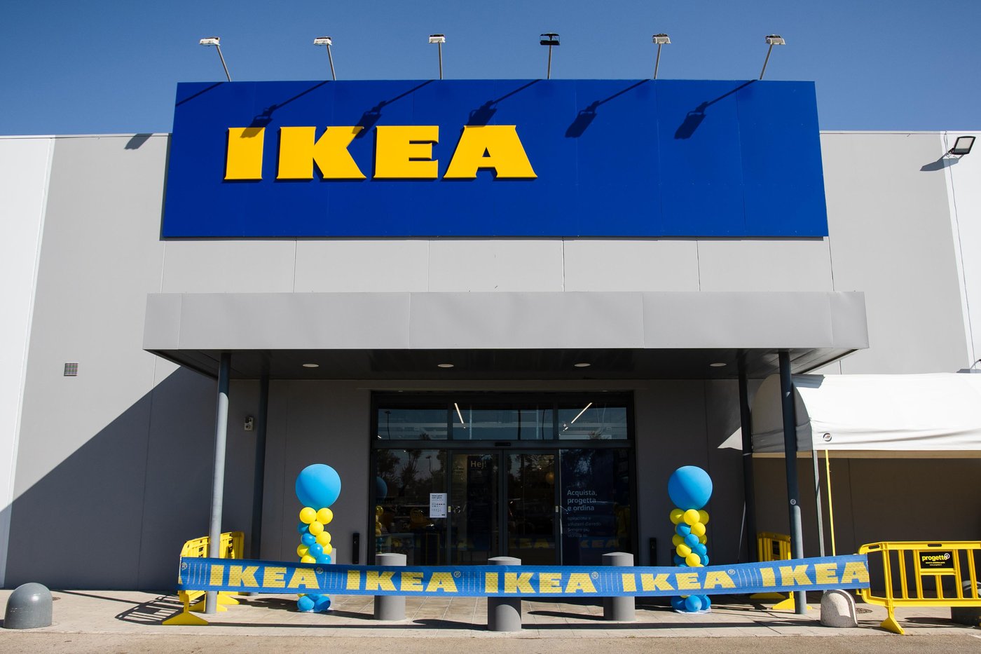 Ingresso del nuovo negozio IKEA Lecce con grande insegna blu e gialla, palloncini decorativi e nastro IKEA davanti alle porte automatiche.