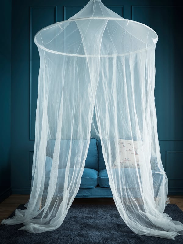In a blue room, a canopy net is hung above a small blue sofa.
