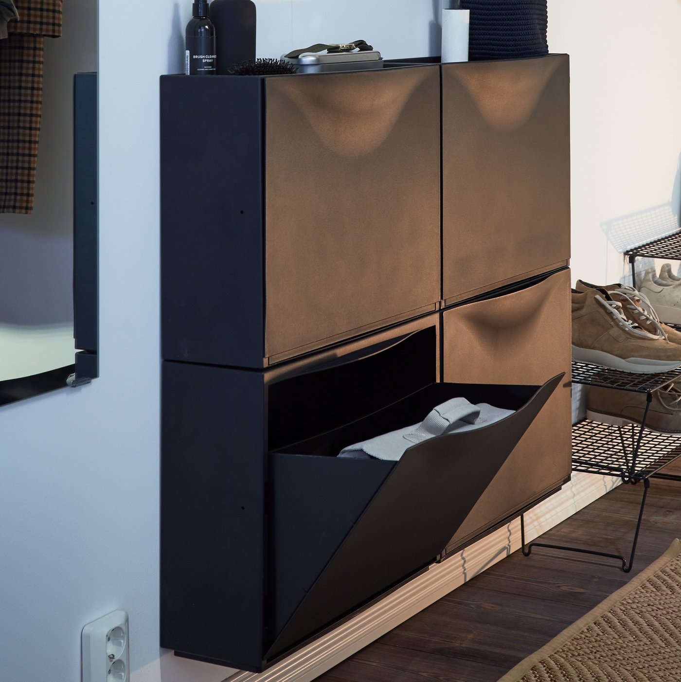 A modern hallway with light walls, dark floors and two sets of TRONES shoe cabinets mounted between a mirror and a shoe rack.
