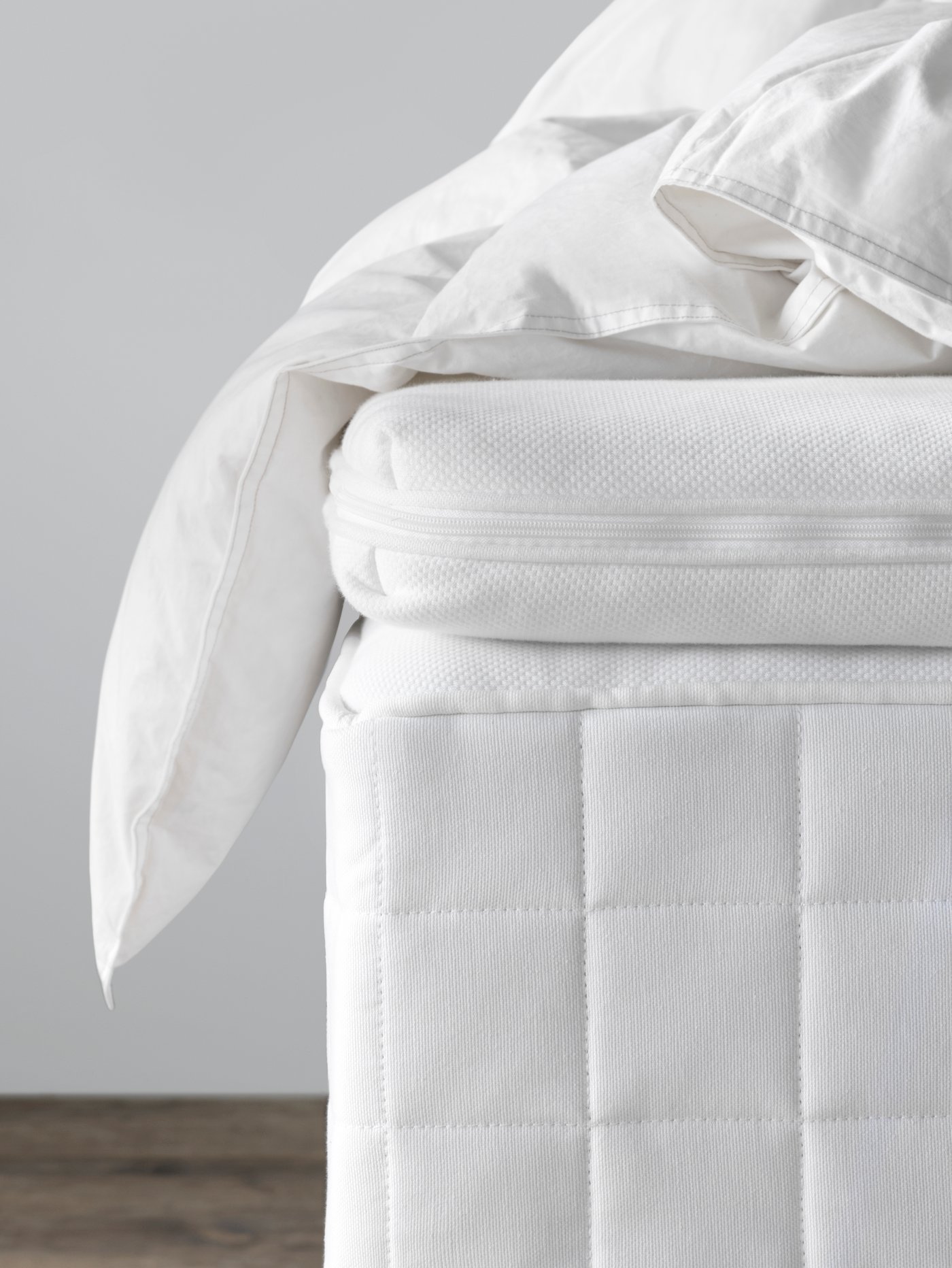 Detalle de un colchón HYLLESTAD y sobre él un topper TUSSÖY y un plumón GRUSBLAD