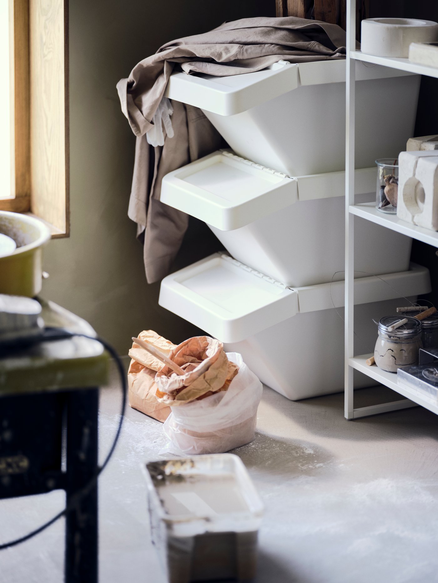 White SORTERA N waste sort bins are placed in a corner of the room beside shelves.