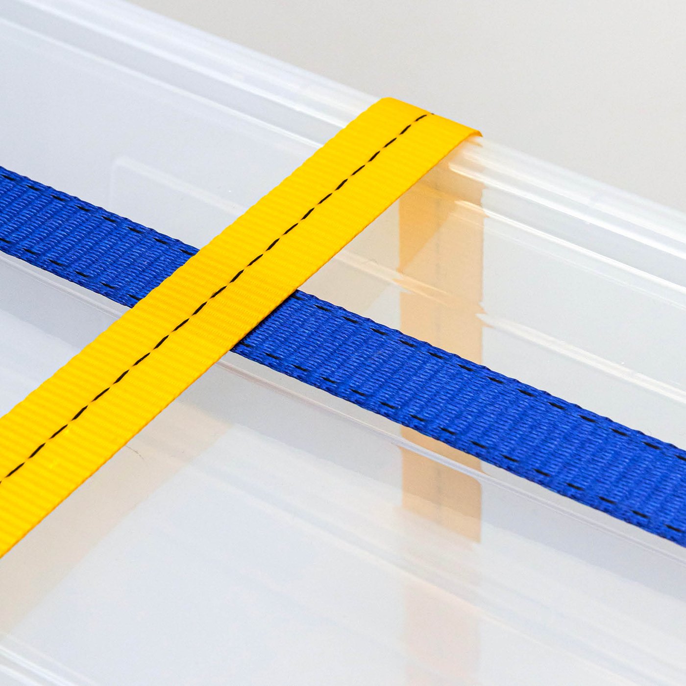 Transparent SAMLA storage box with lid, secured with yellow and blue webbing.