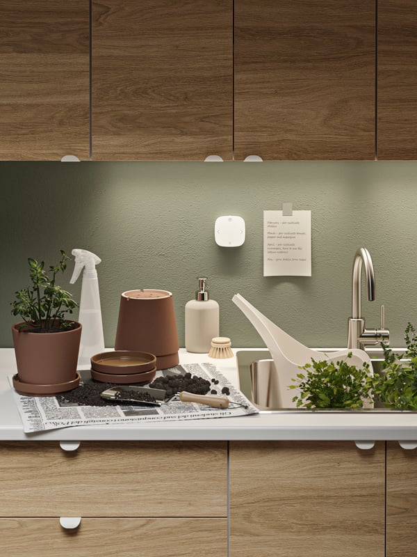 Pots and gardening items on the sink are lit by TRÅDFRI dimmer lights mounted underneath the ENHET cabinets in oak.