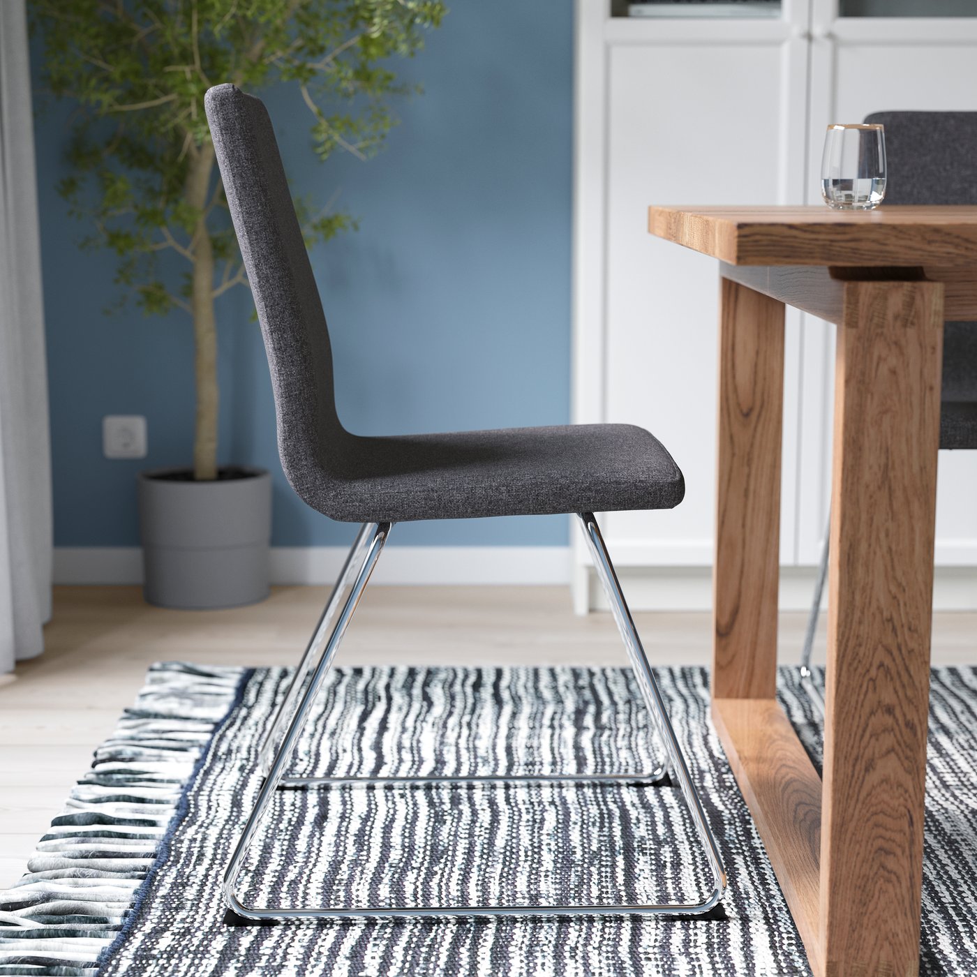 A chrome-plated/Gunnared dark grey LILLÅNÄS chair in the dining room